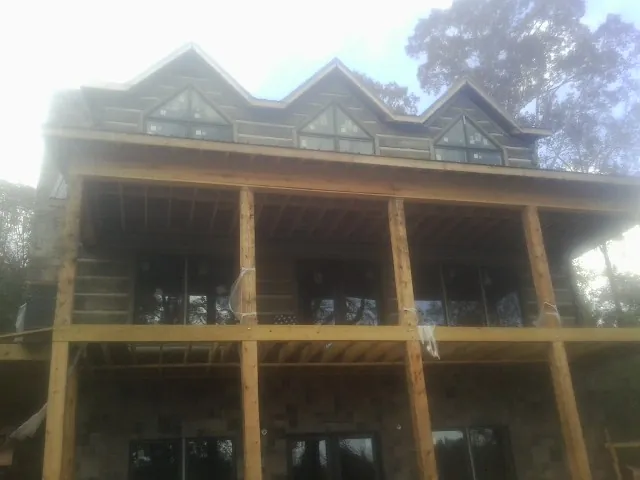 Dormers and porch framing on a large log home under construction — Roof Coating work by our crew in East Nassau