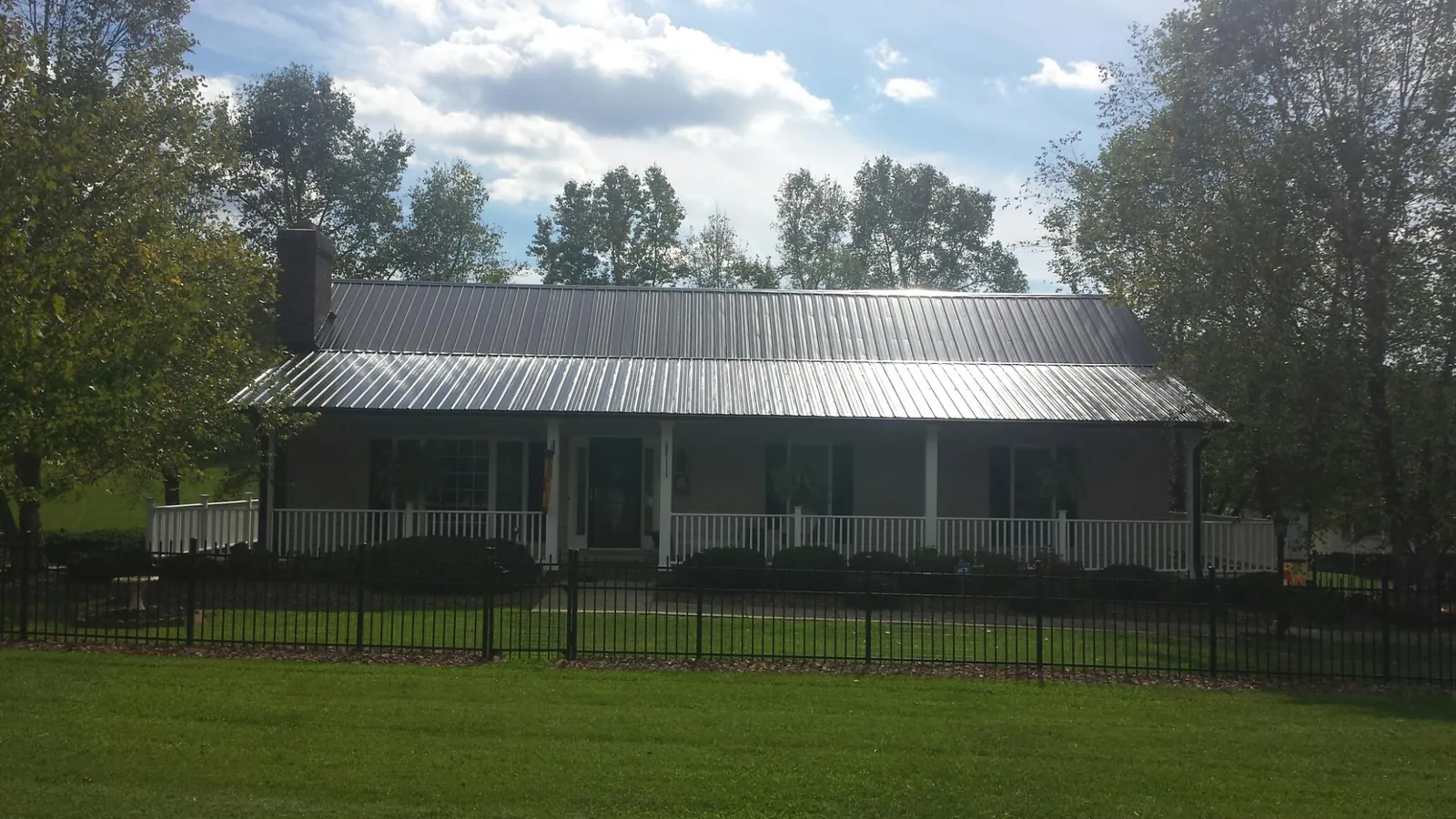 Gray metal roof on a brick ranch with a full width front porch — Gutter Guard Installation work by our crew in East Nassau
