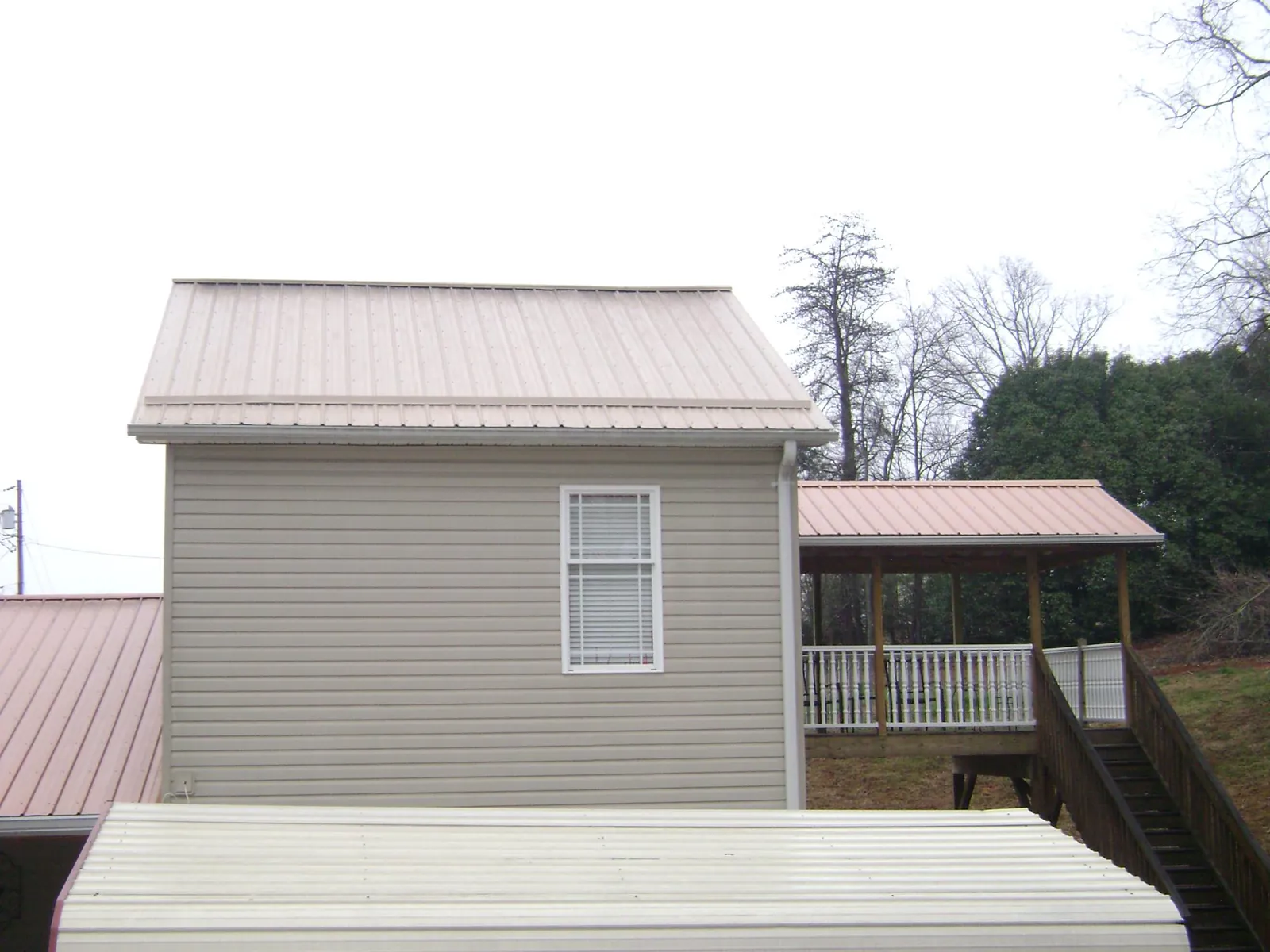 Tan metal roofs on a two story addition and attached porch, from a Roof Replacement job in East Nassau