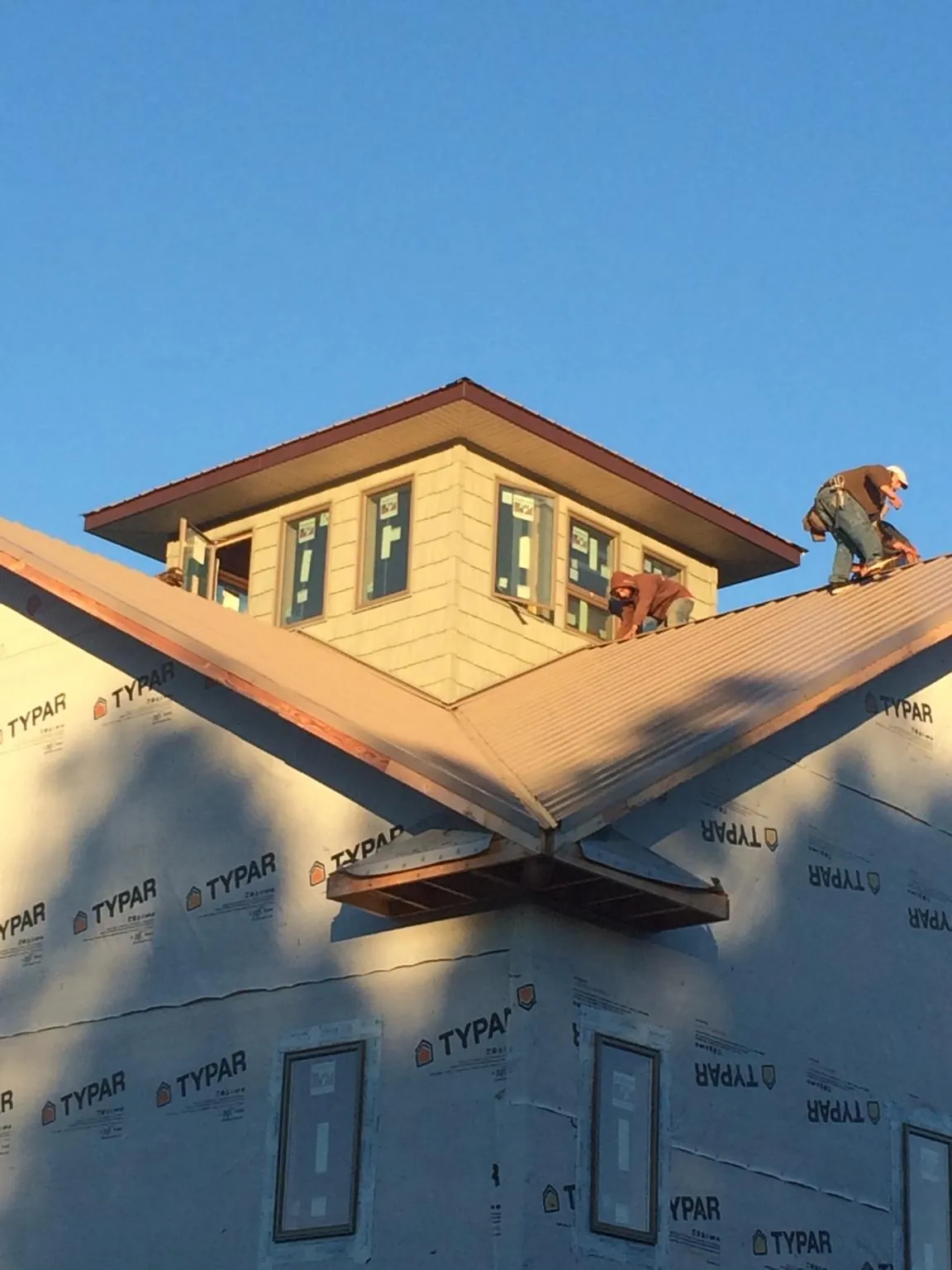 Roofers working around a rooftop cupola on a new metal roof at sunset — Roof Waterproofing in East Nassau by Roofing Brothers